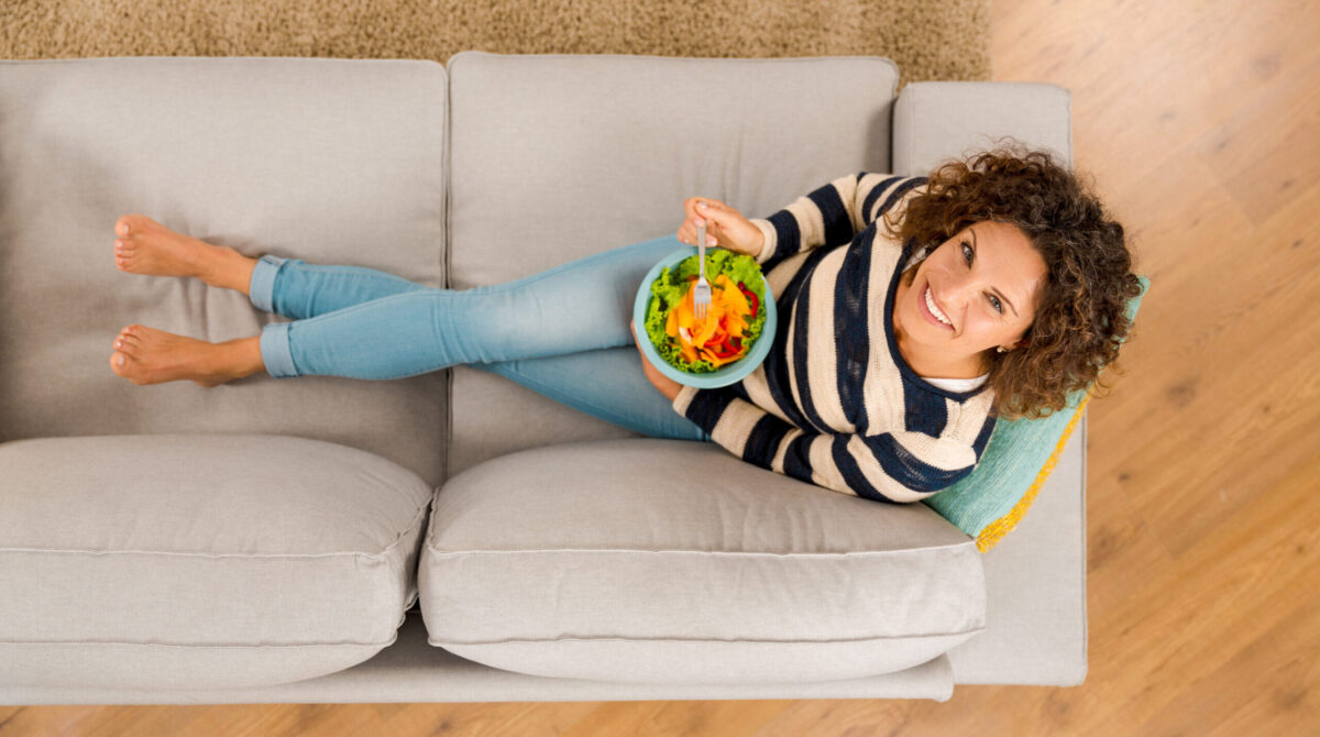 Woman lying on sofa eating a healthy meal